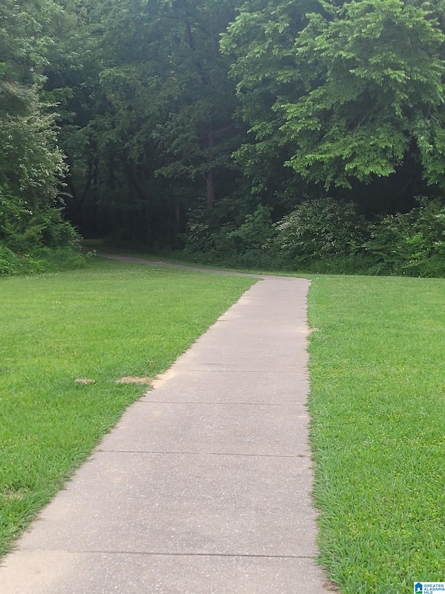 view of community with a lawn and a view of trees