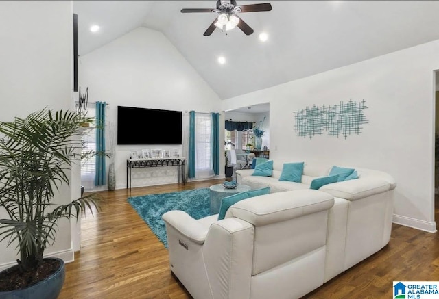 living area with ceiling fan, a wealth of natural light, high vaulted ceiling, and wood finished floors