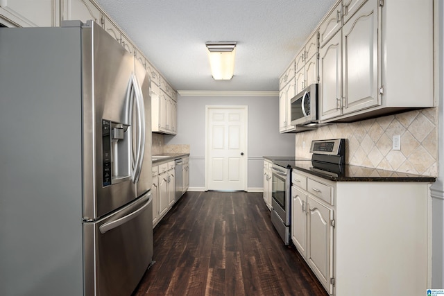 kitchen with dark countertops, crown molding, tasteful backsplash, appliances with stainless steel finishes, and dark wood-style flooring