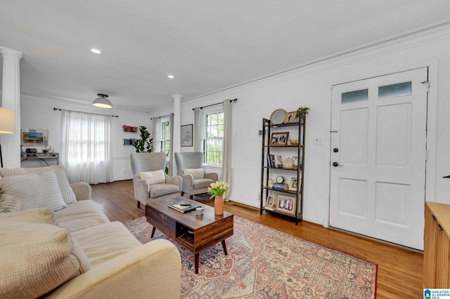 living room with decorative columns, a wealth of natural light, light wood-style floors, and ornamental molding