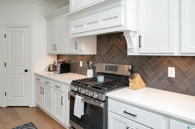 kitchen with white cabinetry, tasteful backsplash, light countertops, and gas range