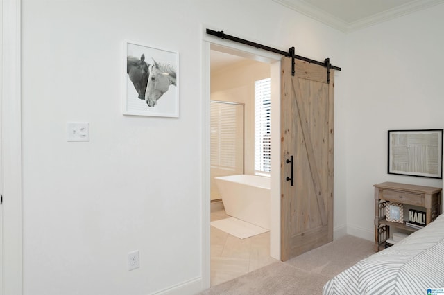 bedroom with a barn door, ensuite bathroom, crown molding, and baseboards