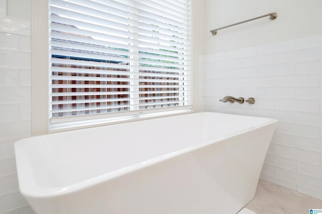 bathroom featuring a soaking tub, tile patterned floors, and tile walls