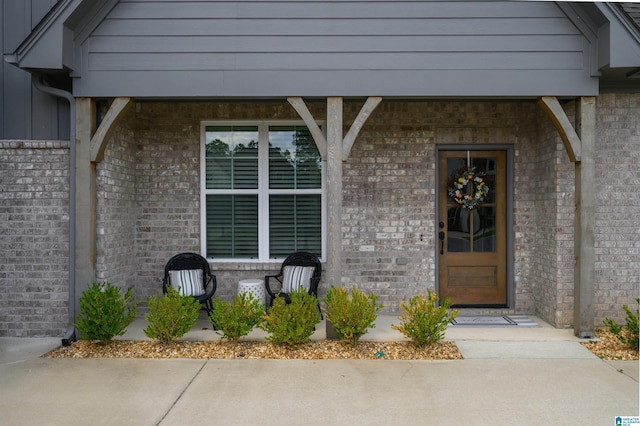 doorway to property featuring board and batten siding and brick siding
