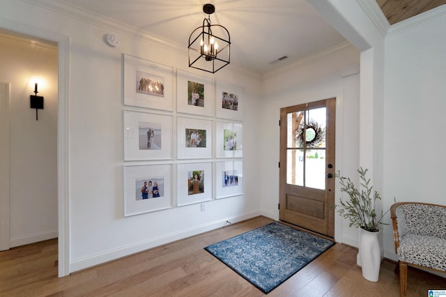 foyer featuring light wood finished floors, an inviting chandelier, crown molding, visible vents, and baseboards