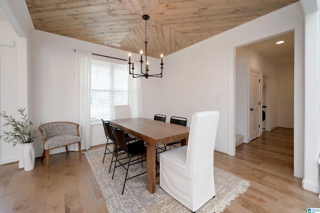 dining area featuring a chandelier, baseboards, crown molding, and light wood finished floors