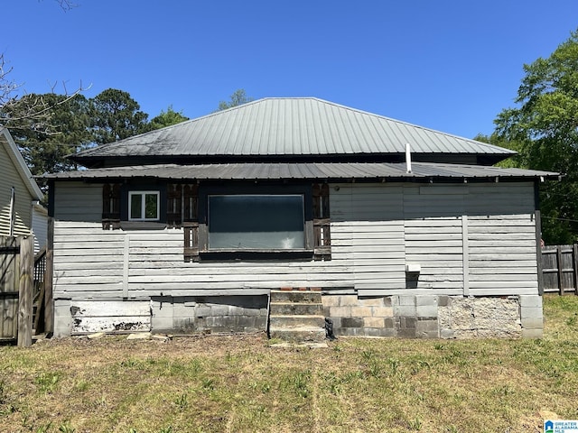exterior space with fence, metal roof, and a lawn