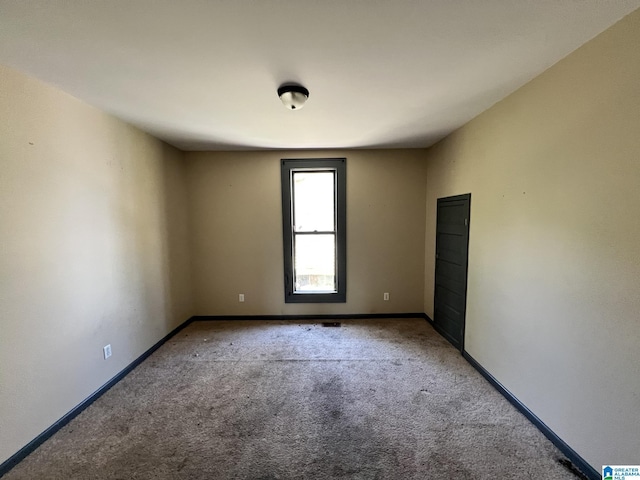 empty room featuring light carpet and baseboards