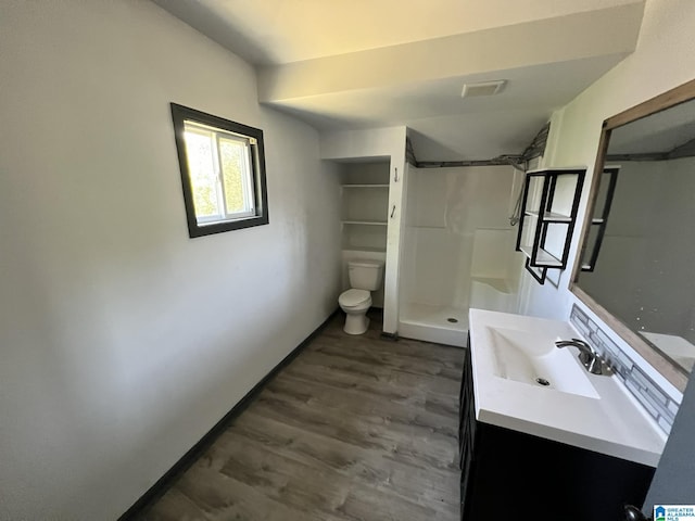 bathroom with visible vents, toilet, vanity, wood finished floors, and a stall shower