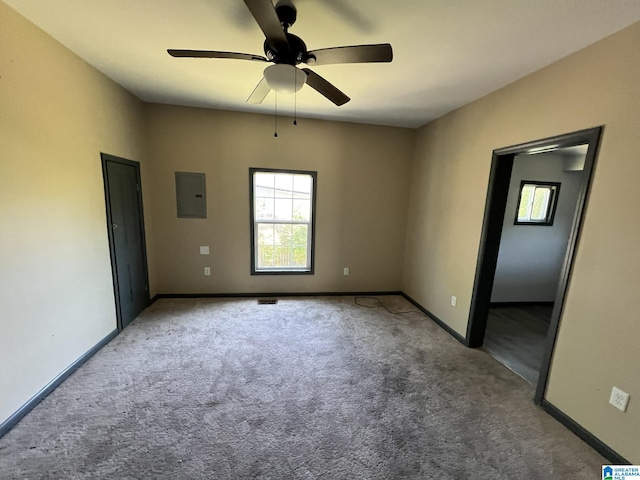 carpeted spare room featuring baseboards, a ceiling fan, and electric panel
