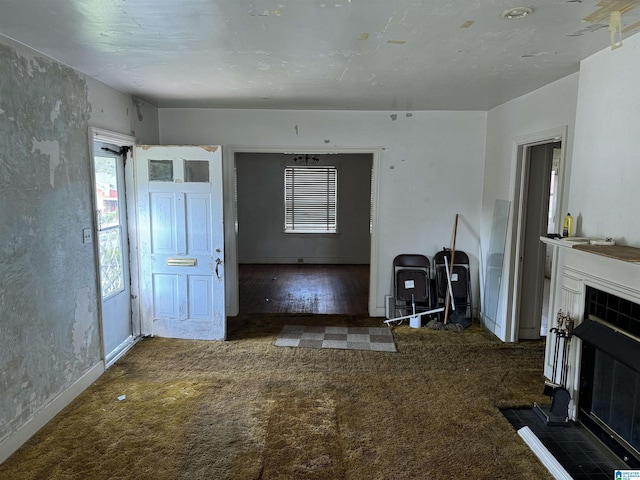 unfurnished living room featuring baseboards, a tiled fireplace, and carpet