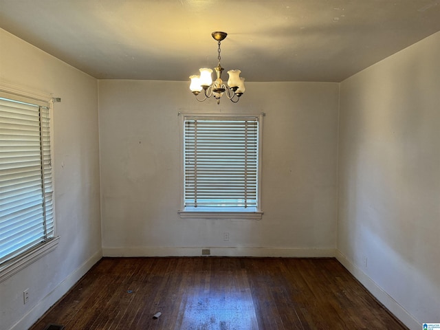 spare room with a chandelier, wood-type flooring, baseboards, and a healthy amount of sunlight