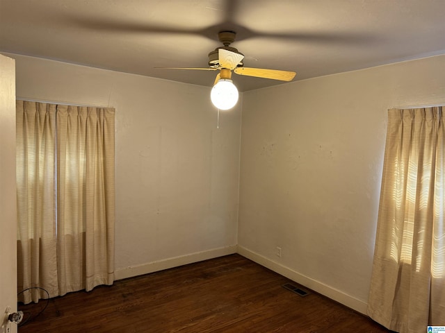 spare room featuring dark wood-type flooring, visible vents, ceiling fan, and baseboards