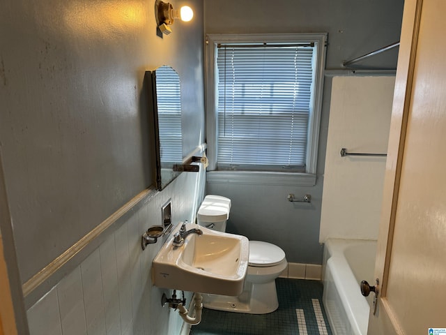 full bathroom featuring tile patterned floors, wainscoting, a sink, and toilet