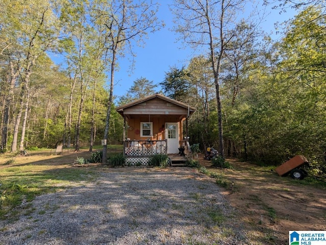 view of front of property featuring covered porch and a forest view