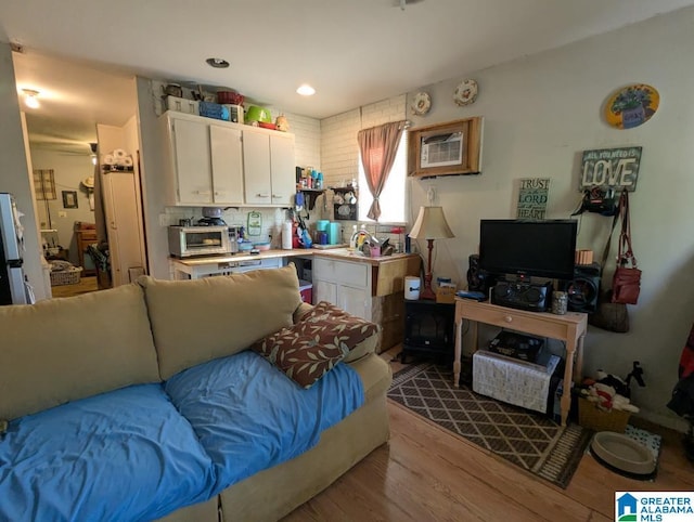 living area with a toaster, wood finished floors, and a wall unit AC