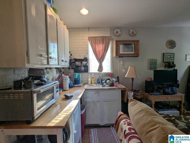 kitchen with tasteful backsplash, butcher block countertops, a sink, and a wall mounted air conditioner