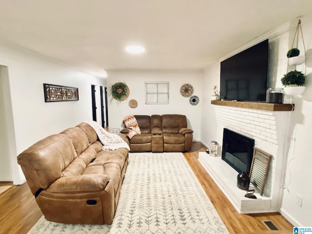 living area featuring a fireplace, visible vents, recessed lighting, wood finished floors, and baseboards