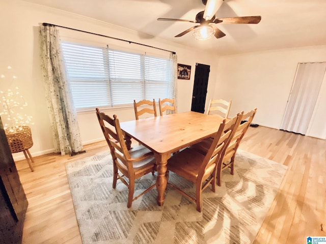 dining space featuring light wood-style flooring, baseboards, and a ceiling fan