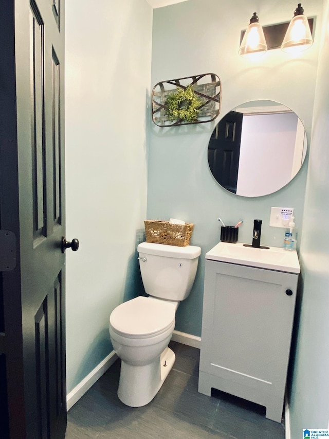 half bathroom featuring toilet, wood finished floors, vanity, and baseboards