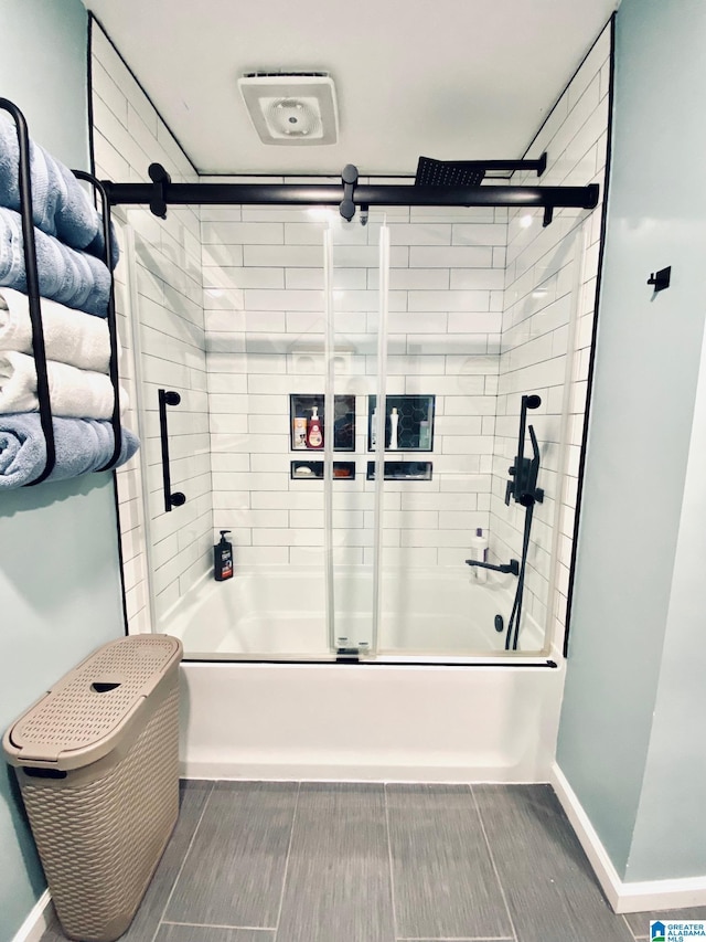 full bath featuring baseboards, wood finish floors, and bath / shower combo with glass door