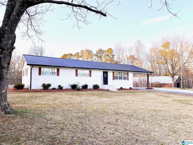 single story home featuring a carport, metal roof, a front yard, and driveway