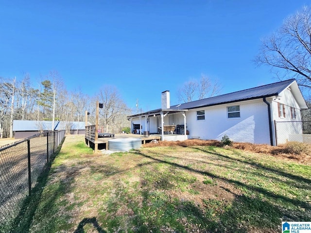 back of house featuring a yard, a fenced backyard, metal roof, and a chimney