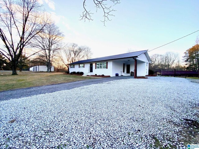 ranch-style home featuring a front yard, fence, metal roof, and gravel driveway