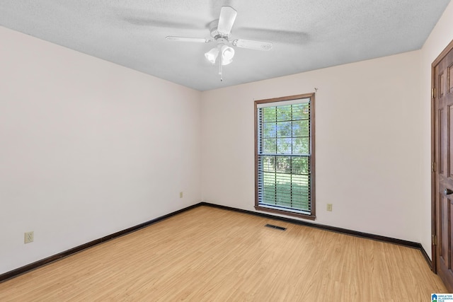 spare room featuring light wood-style flooring, visible vents, baseboards, and ceiling fan