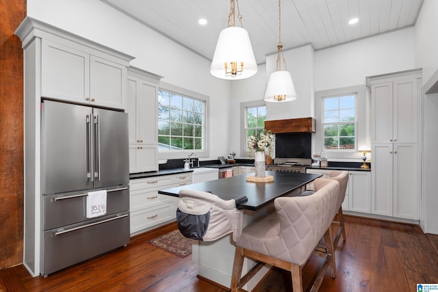 kitchen with dark wood-style flooring, high end refrigerator, dark countertops, and recessed lighting