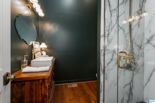 interior space featuring wood finished floors, visible vents, vanity, and a marble finish shower