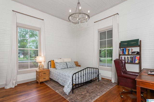 bedroom with a chandelier, wood finished floors, and baseboards