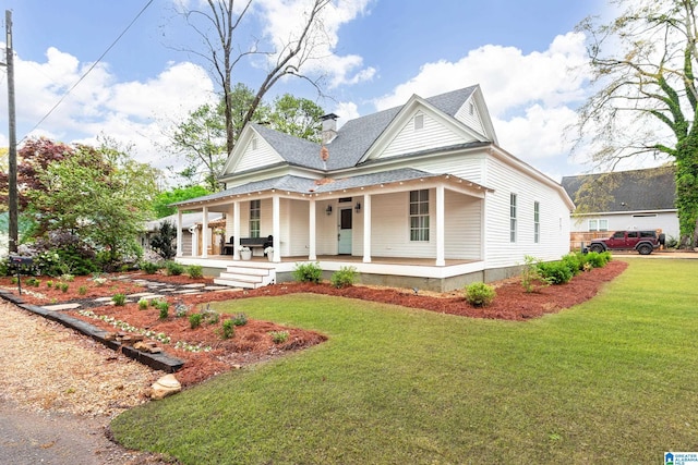 view of front of property with a shingled roof, a front lawn, and covered porch
