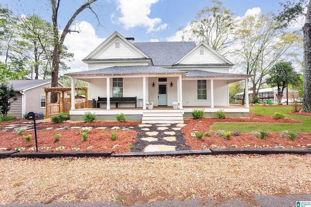 farmhouse inspired home featuring roof with shingles and covered porch