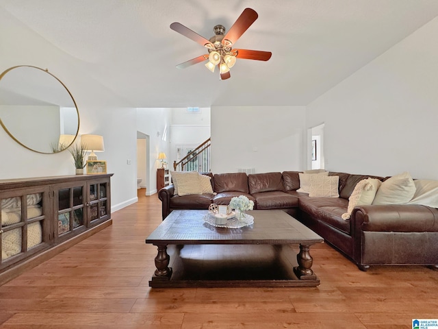 living room featuring light wood finished floors, a ceiling fan, visible vents, and stairway