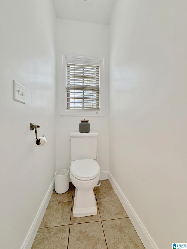 bathroom featuring baseboards, tile patterned flooring, and toilet