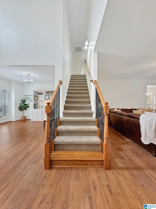 staircase featuring a notable chandelier, wood finished floors, and plenty of natural light
