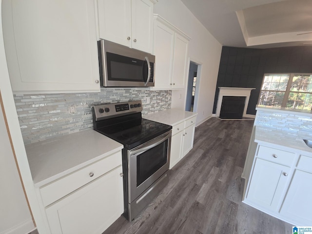 kitchen featuring white cabinets, light countertops, stainless steel appliances, open floor plan, and decorative backsplash
