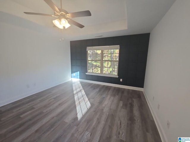 spare room featuring baseboards, wood finished floors, and ceiling fan
