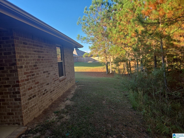 view of side of home featuring brick siding and a lawn