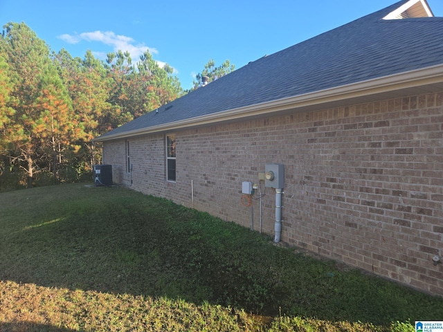 view of property exterior with cooling unit, a yard, a shingled roof, and brick siding