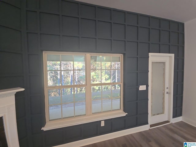 doorway with dark wood-type flooring, a wealth of natural light, and baseboards