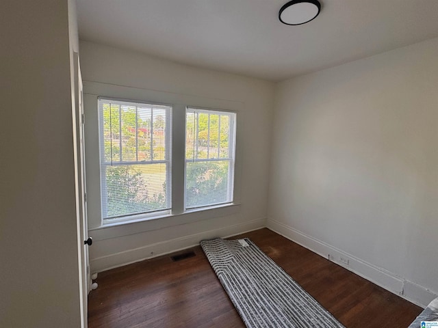 spare room with dark wood finished floors, baseboards, and visible vents