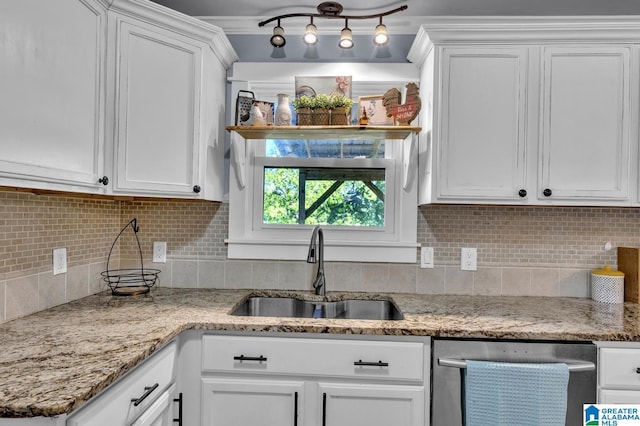 kitchen with stainless steel dishwasher, a sink, and white cabinetry