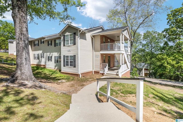 exterior space featuring covered porch, a lawn, and a balcony