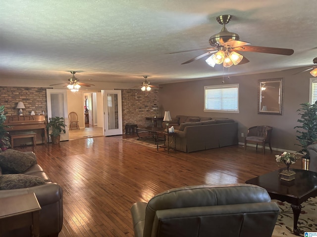 living area with hardwood / wood-style floors, a fireplace, baseboards, a ceiling fan, and a textured ceiling