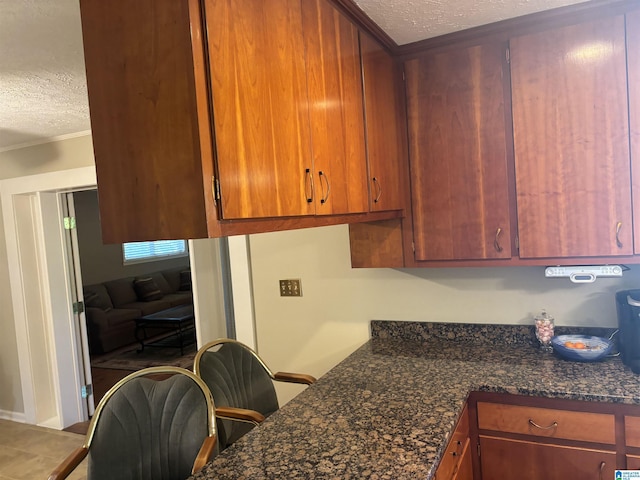 kitchen featuring crown molding, a textured ceiling, and brown cabinetry