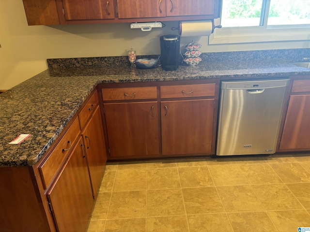 kitchen featuring stainless steel dishwasher, brown cabinetry, and dark stone counters