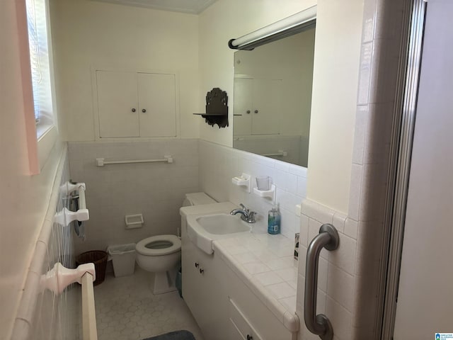 bathroom with toilet, vanity, tile patterned flooring, and tile walls