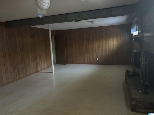 basement with wooden walls, a fireplace, and light floors